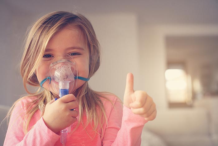 little girl using inhaler