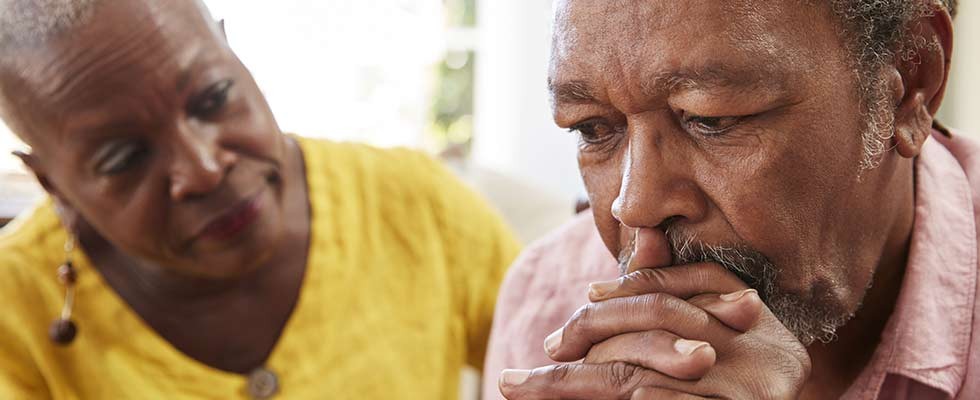 black senior woman comforts black senior man