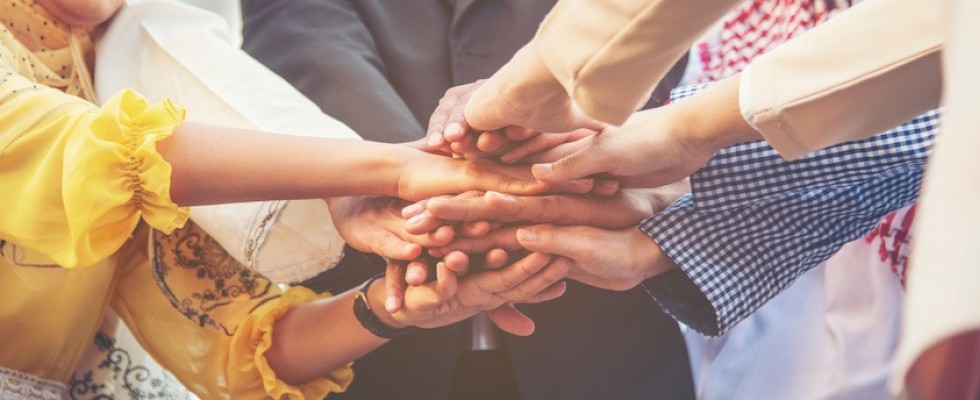 Multiple people in a huddle putting their hands in. 