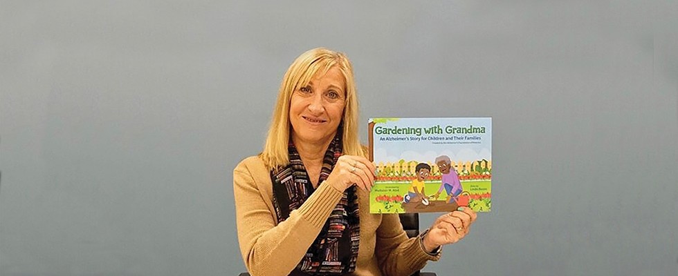 An image of a woman holding up the book "Gardening with Grandma"