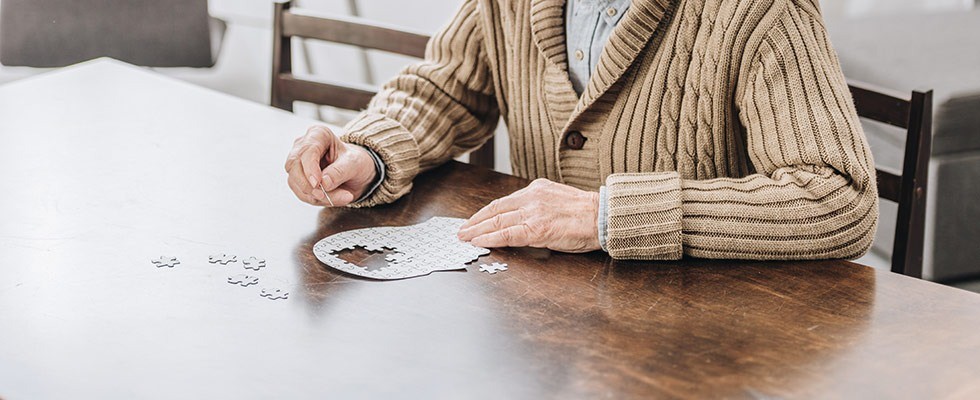 Man putting together a head-shaped puzzle at a table.