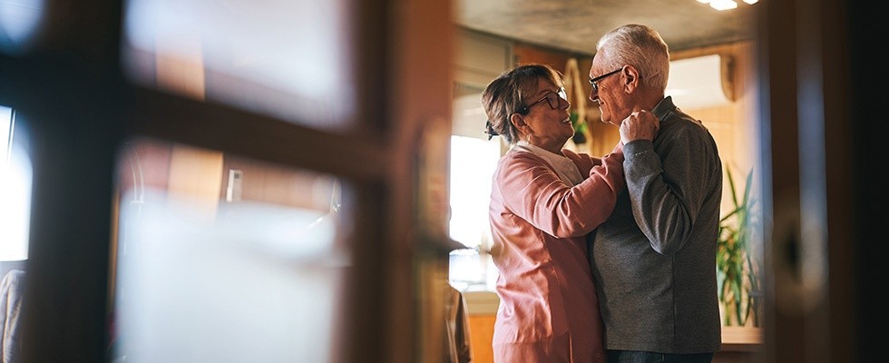 Older couple dancing in their home.