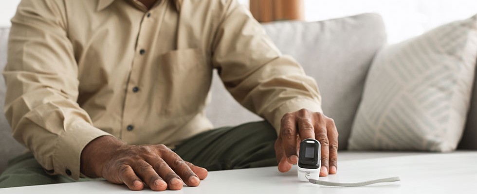 Black man checks oxygen levels using spirometer