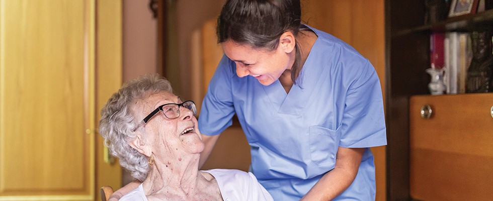 Homecare nurse laughing with senior patient.