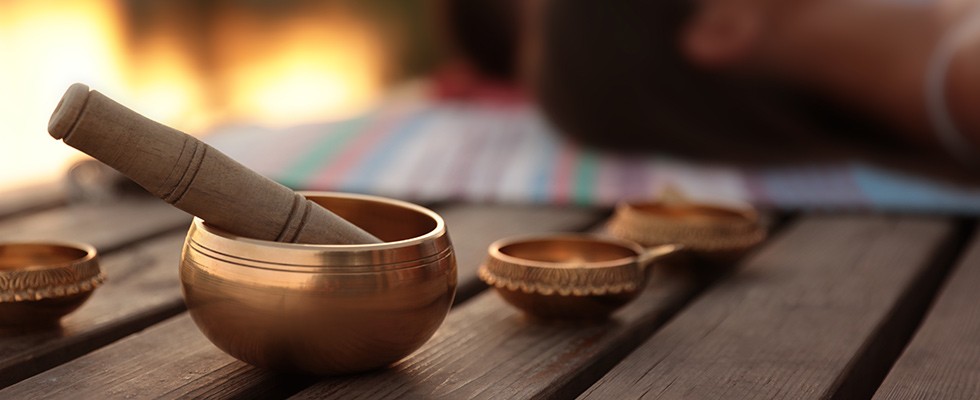 Wooden and copper bowls on a table outdoors, with people blurred out in the background.