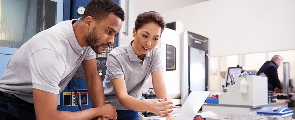 Two people look at a computer in an office