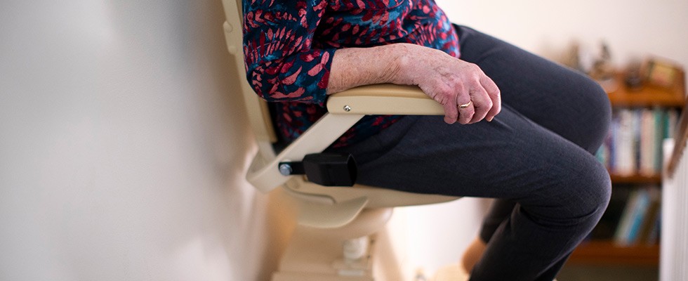 Older adult woman using a lift machine in their home to go down stairs