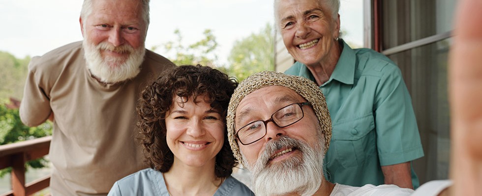 Two older men, an older woman, and a younger woman all smiling for a photo together.