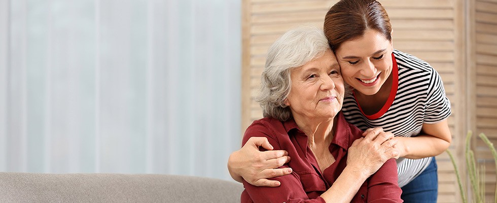 An older woman being hugged by a younger woman. 