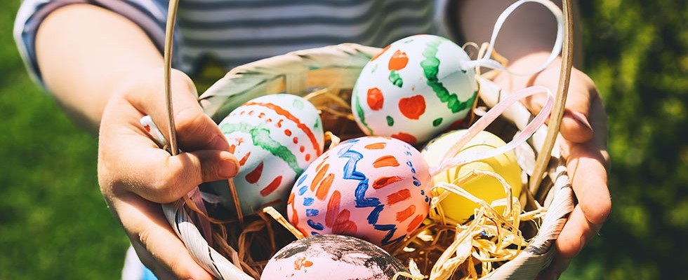 Five colorful Easter eggs in a basket held by a small child