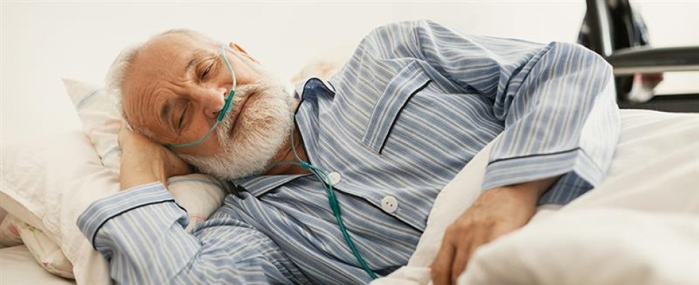 Man lying in bed while using oxygen equipment. 