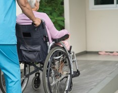 Older woman being pushed in a wheelchair by a caregiver.