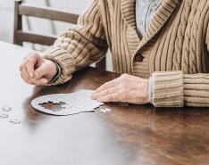 Man putting together a head-shaped puzzle at a table.