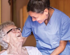 Homecare nurse laughing with senior patient.