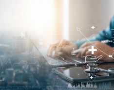 City skyline on the left that fades into a laptop on a desk being used, with illustrations of plus signs and chart graphs.