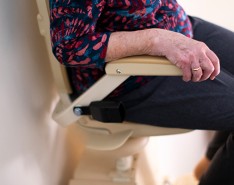 Older adult woman using a lift machine in their home to go down stairs