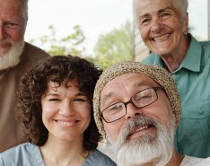 Two older men, an older woman, and a younger woman all smiling for a photo together.