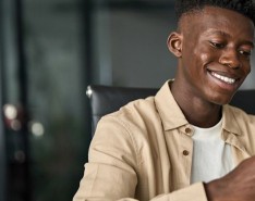 A young man smiles while looking at his cell phone.
