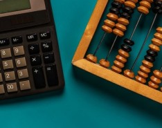 A calculator and an abacus on a teal background