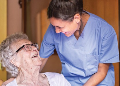 Homecare nurse laughing with senior patient.