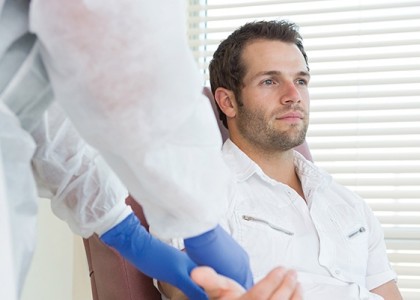 Man sits in a chair, getting his arm examined by a nurse.