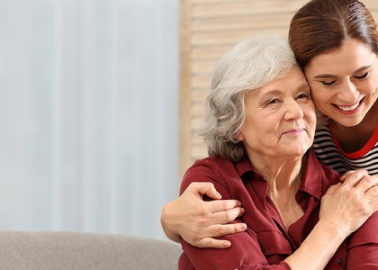 An older woman being hugged by a younger woman. 
