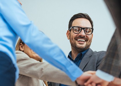 A group of people have their hands together for a group cheer. 